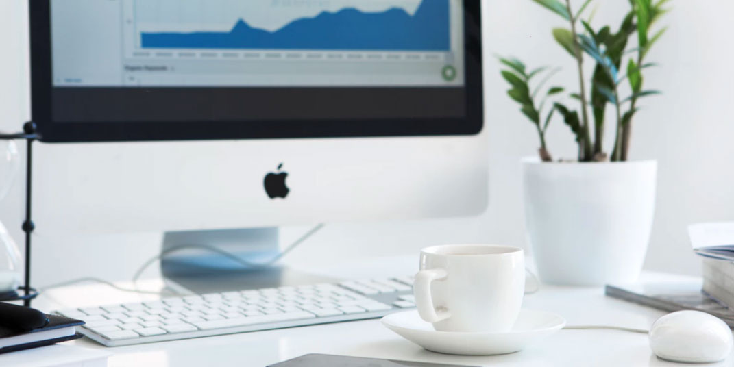 iMac on desk with coffe cup and plant